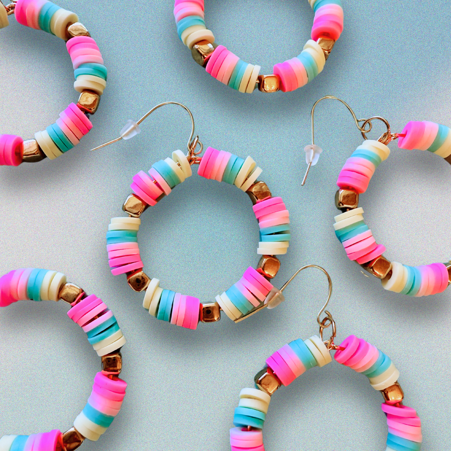 A pair of hot pink, pastel pink, teal, and yellow hoop earrings with gold accents, inspired by cotton candy, for a fun and whimsical jewelry statement.