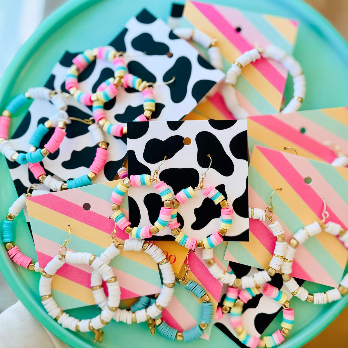 A pair of hot pink, pastel pink, teal, and yellow hoop earrings with gold accents, inspired by cotton candy, for a fun and whimsical jewelry statement.