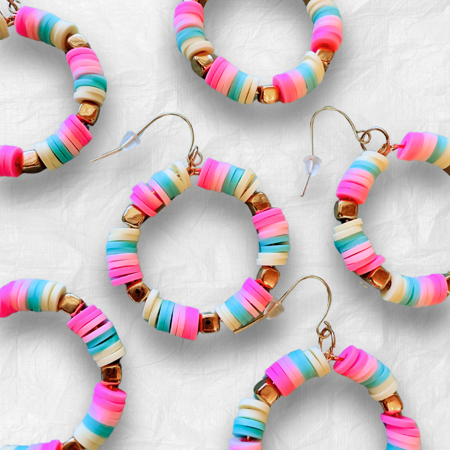 A pair of hot pink, pastel pink, teal, and yellow hoop earrings with gold accents, inspired by cotton candy, for a fun and whimsical jewelry statement.