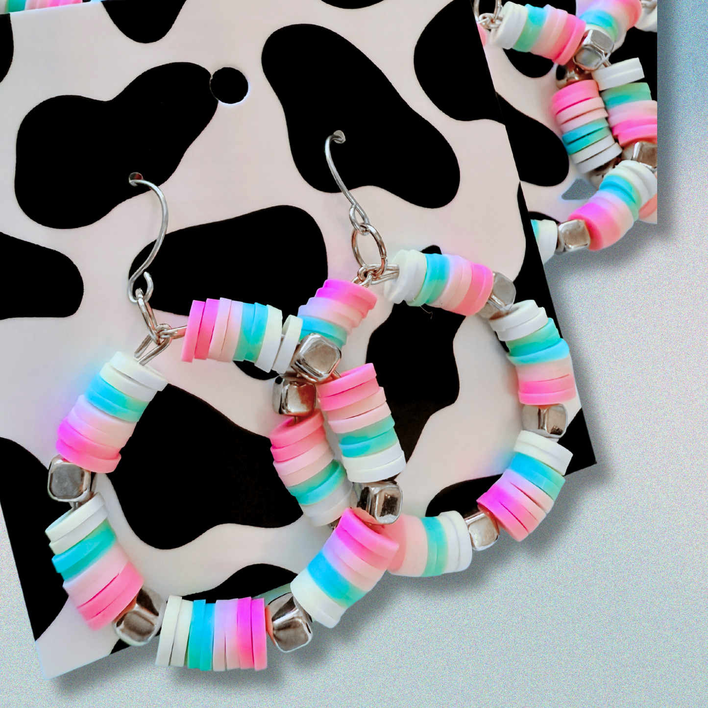 A pair of hot pink, pastel pink, teal, and yellow hoop earrings with gold accents, inspired by cotton candy, for a fun and whimsical jewelry statement.
