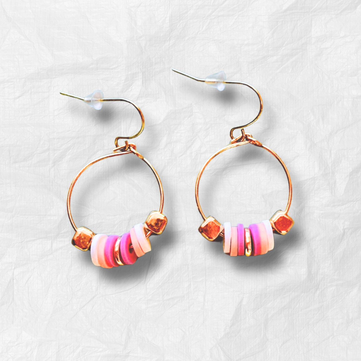A pair of delicate gold mini hoop earrings featuring soft pink and white beaded accents, presented on a warm-toned Stella & Moo branded card, perfect for a fun yet minimal statement look.