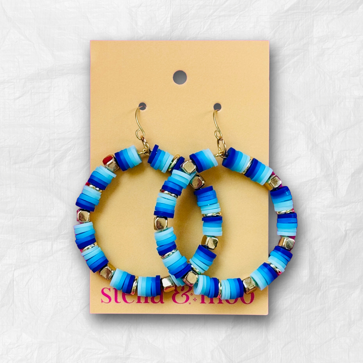 A pair of handcrafted blue and gold beaded hoop earrings with ocean-inspired hues, displayed on a neutral background for a bold yet elegant look.