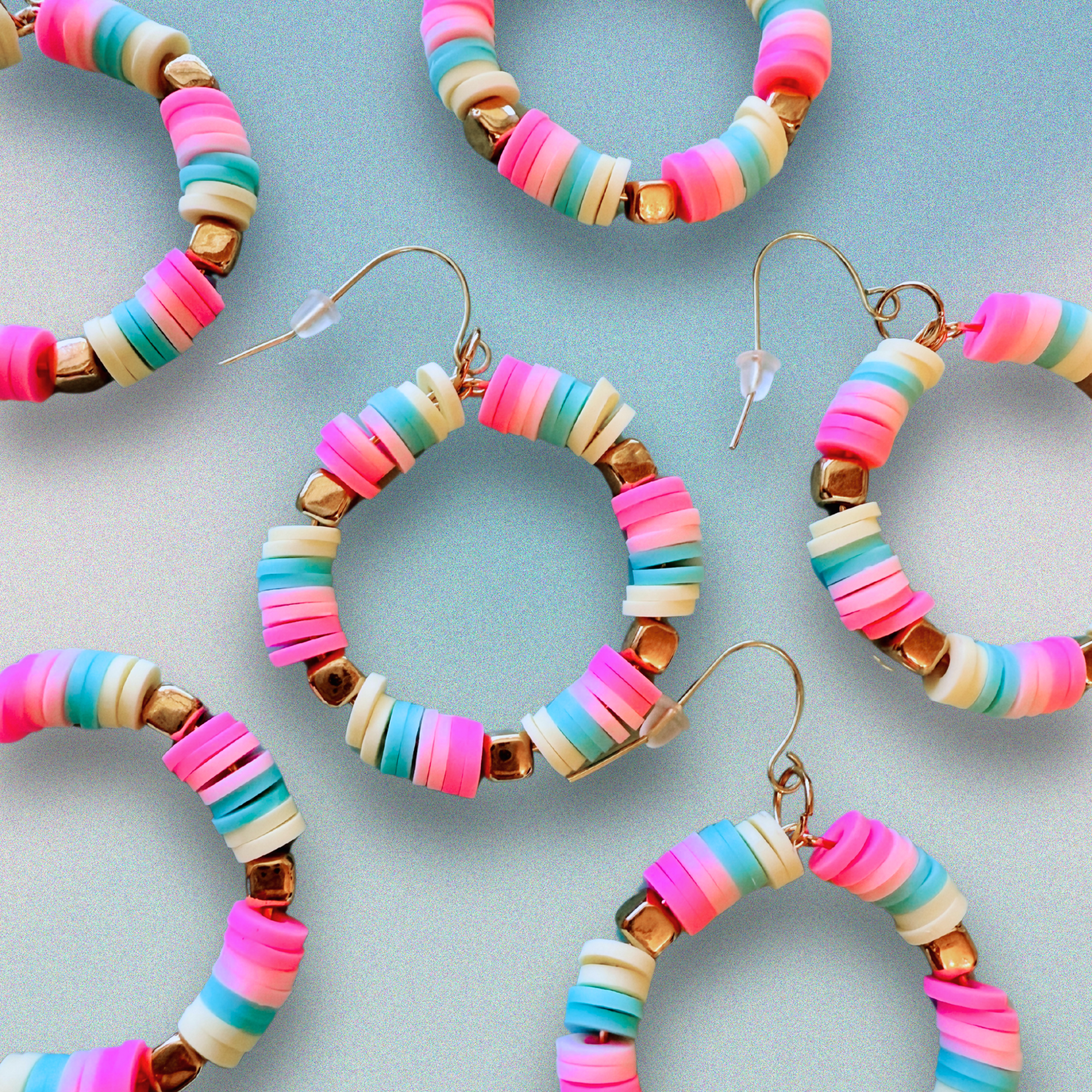 A pair of hot pink, pastel pink, teal, and yellow hoop earrings with gold accents, inspired by cotton candy, for a fun and whimsical jewelry statement.