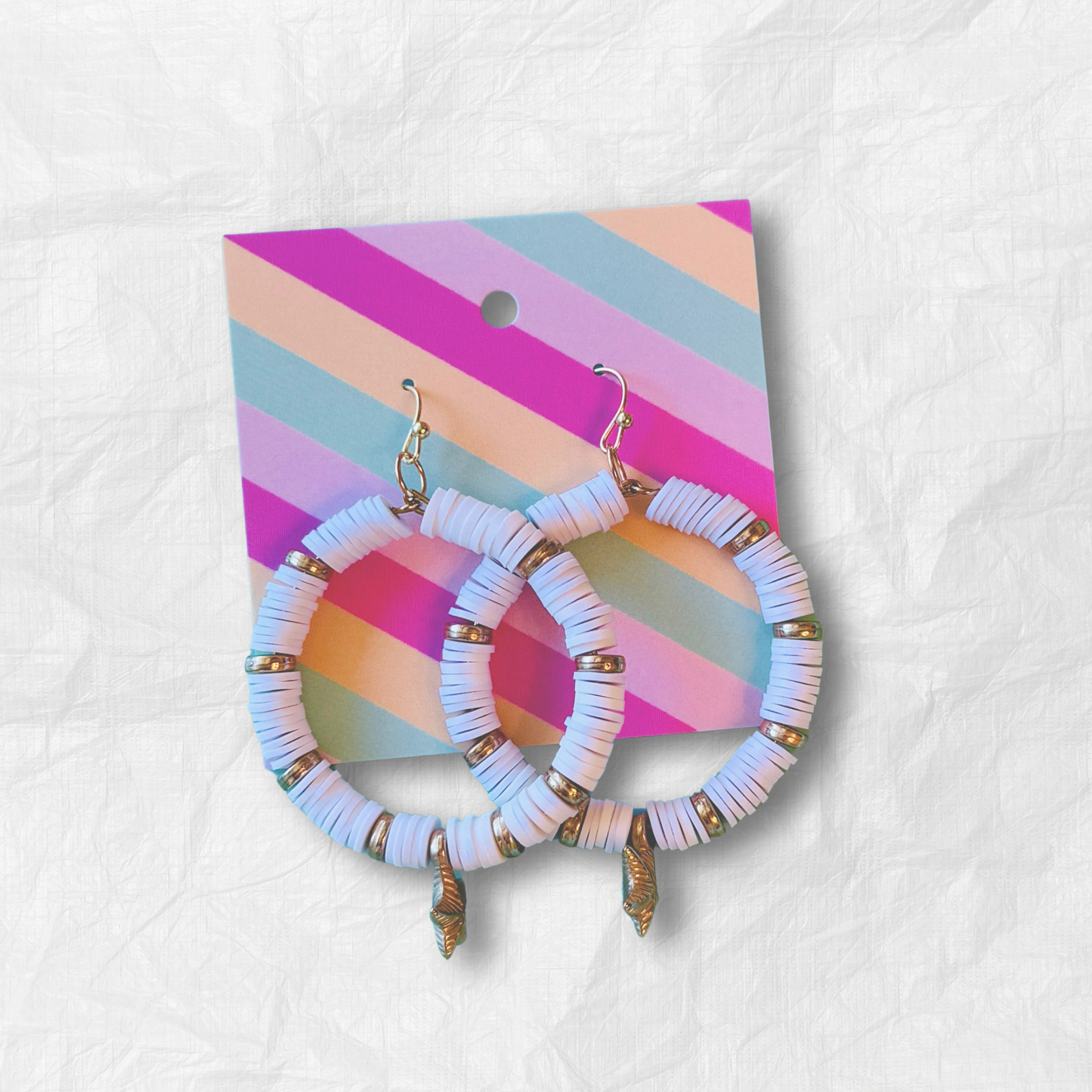 A pair of white and gold starfish hoop earrings with coastal-inspired heishi beads and shimmering accents, designed for a beachy and elegant aesthetic against a soft blue background.